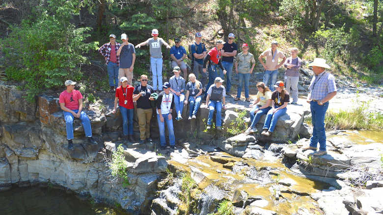 Group of young people standing together on a cliff in the mountains