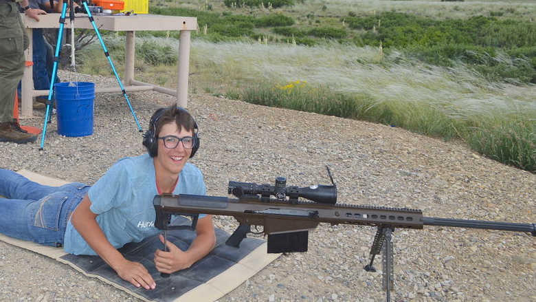 Excited young man laying prone with a long-range rifle.