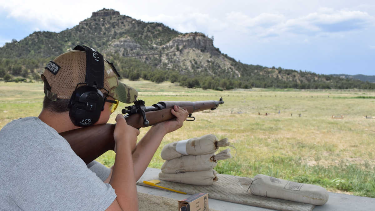 Young man shooting a rifle at an outdoor range at the NRA Whittington Center Adventure Camp in New Mexico