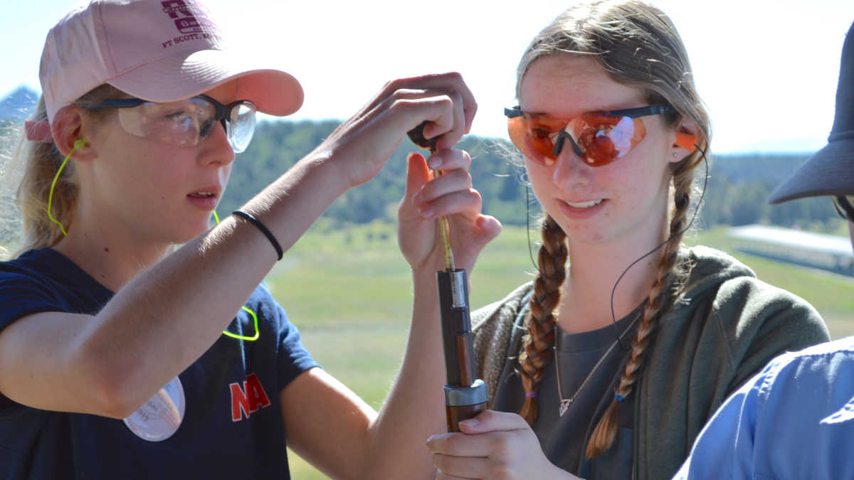 Girls load a musket at the NRA Whittington Center Adventure Camp in New Mexico mountains. 